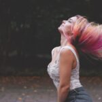 Frau wirft ihre Haare nach hinten als Symbol für Kopfhaut und Haarpflege bei Kopfläusen